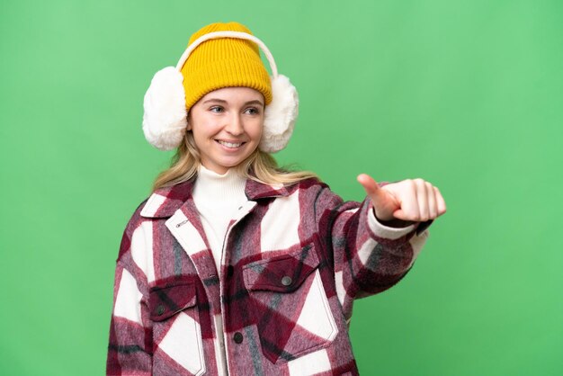 Młoda Angielka ubrana w zimowe mufki na odizolowanym tle, pokazująca kciuk w górę