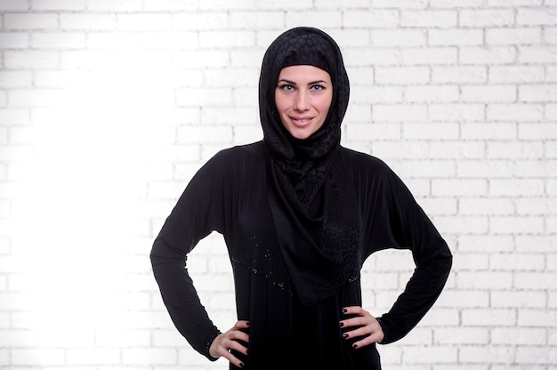 Młoda arabska kobieta ubrana w tradycyjny strój arabski pozuje kryty.