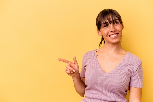 Młoda argentyńska kobieta na białym tle na żółtym tle uśmiechając się radośnie wskazując palcem wskazującym.
