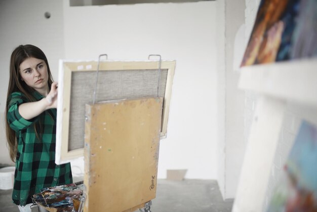 Młoda artystka pracująca w warsztacie maluje szczotką inspirację do płótna