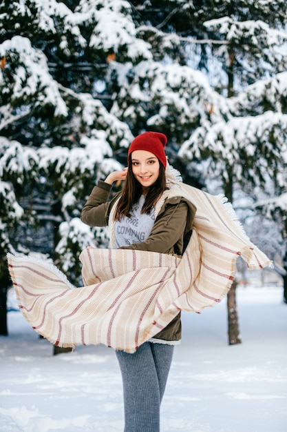 Młoda atrakcyjna brunetka dziewczyna pozuje z latającą peleryną w lesie śniegu