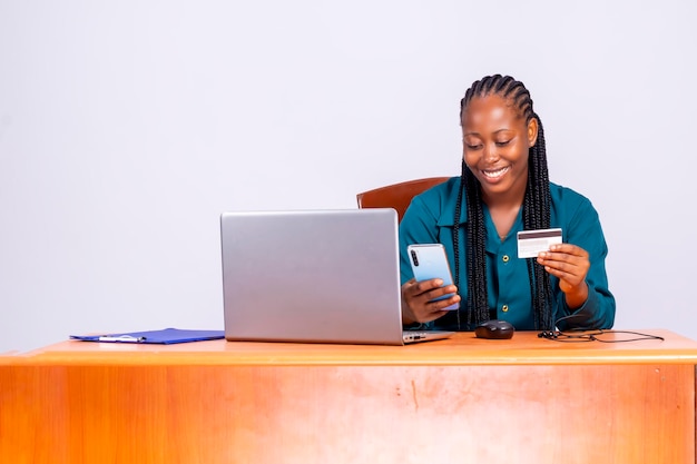 Młoda atrakcyjna czarna afrykańska szczęśliwa kobieta za pomocą karty kredytowej robi zakupy online z komputerem...