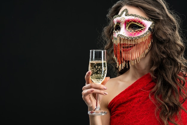 Zdjęcie młoda atrakcyjna kobieta jest ubranym venetian karnawał maskę przeciw czarnemu tłu