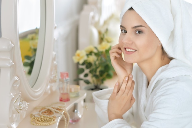 Młoda atrakcyjna kobieta robi makijaż po prysznicu w buduarze
