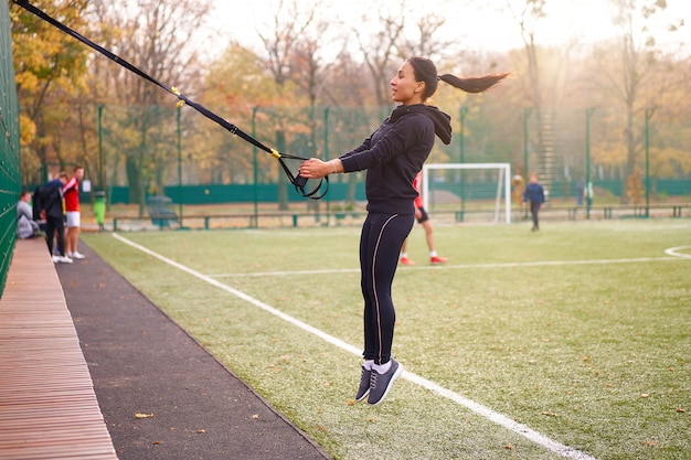 Młoda Atrakcyjna Kobieta Robi Trening Zawieszenia Z Paskami Fitness Na świeżym Powietrzu