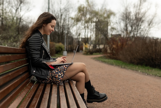 Młoda atrakcyjna kobieta siedzi w parku z laptopem