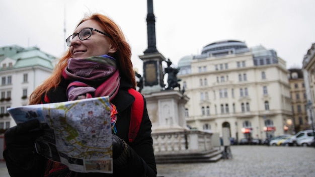 Zdjęcie młoda atrakcyjna rudowłosa kobieta korzystająca z mapy miasta w wiedniu, szeroki kąt