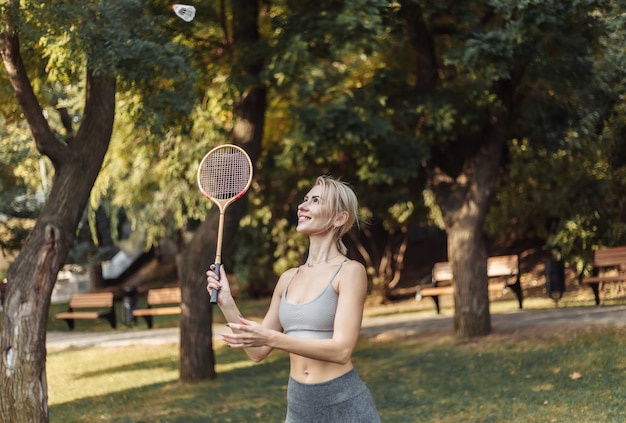 Młoda atrakcyjna sportowa kobieta gra w badmintona w parku