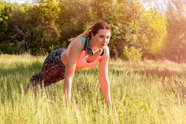Młoda atrakcyjna szczupła kobieta w sportowych ubraniach robi joga medytując w parku z sosnami w tle Koncepcja zdrowego stylu życia
