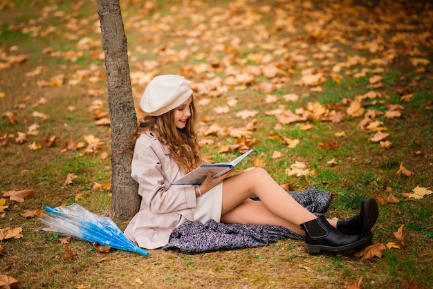 Młoda atrakcyjna uśmiechnięta dziewczyna pod parasolem w lesie jesienią