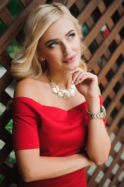 Młoda atrakcyjna żeńska blondynki kobieta w czerwieni sukni obsiadaniu na krześle