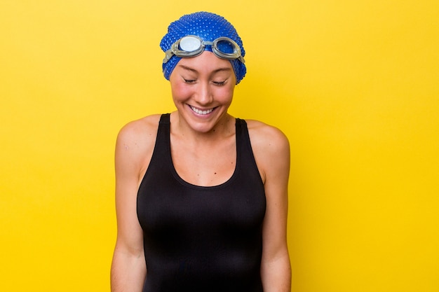 Zdjęcie młoda australijska pływaczka na żółtym tle śmieje się i zamyka oczy, czuje się zrelaksowana i szczęśliwa.