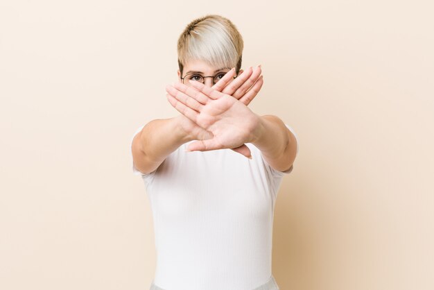 Młoda autentyczna naturalna kobieta w białej koszuli robi gest odmowy