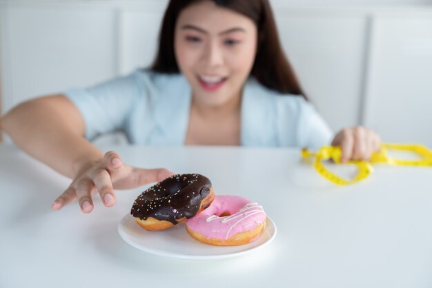 Młoda Azjatka Sięga Po Pączki, Próbując Stosować Dietę