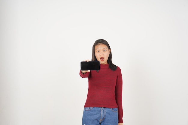 Młoda Azjatka w czerwonej koszulce Wow Szokowana i pokazująca pusty ekran smartfona izolowany na białym tle