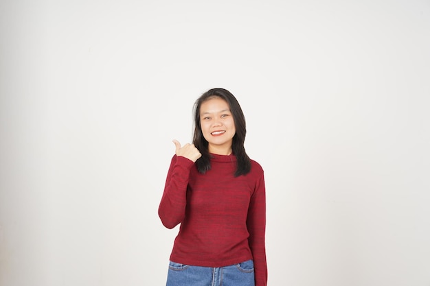 Młoda Azjatka w czerwonej koszulce wskazuje z boku na przestrzeń do kopiowania z kciukiem wyizolowanym na białym tle