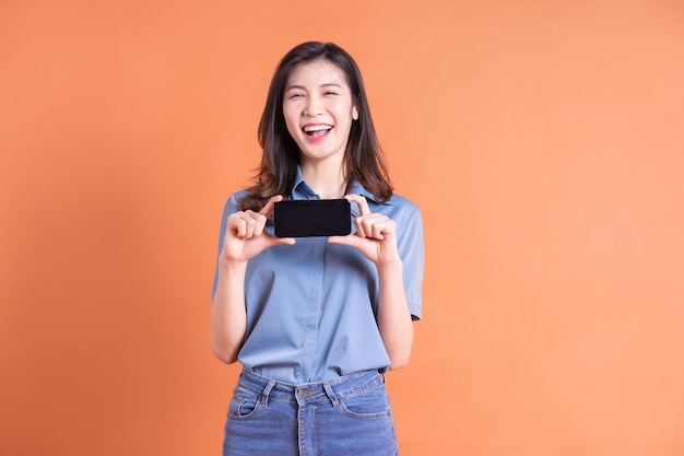 Młoda azjatycka biznesowa kobieta pozuje na pomarańczowym tle