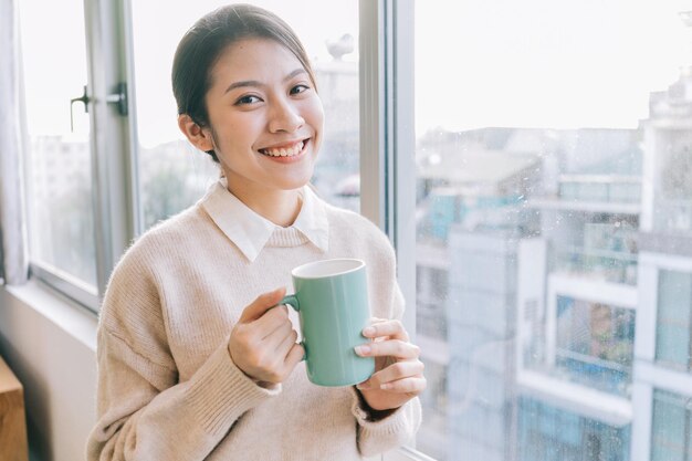 Młoda azjatycka bizneswoman pije herbatę rano