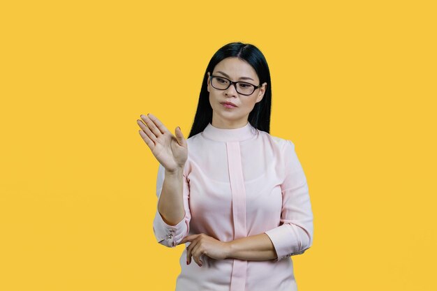 Młoda azjatycka bizneswoman przesuwa niewidoczny ekran dotykowy odizolowany na żółtym tle