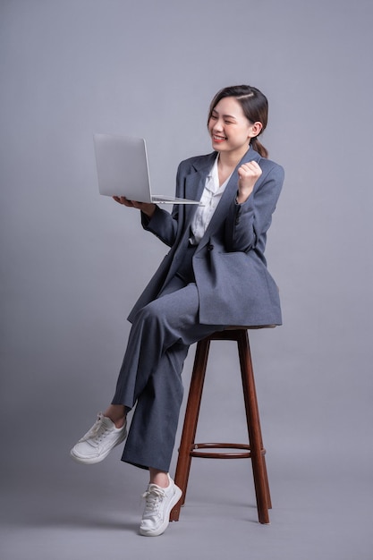 Młoda Azjatycka Bizneswoman Siedzi Na Krześle I Korzysta Z Laptopa Na Szarym Tle