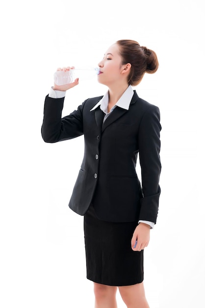 Młoda azjatycka bizneswoman w czarnym garniturze i białej koszuli pijąca zimną wodę z butelki na białym tle