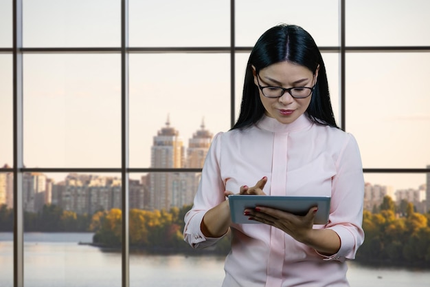 Młoda Azjatycka Bizneswoman W Okularach Używa Komputera Typu Tablet W Biurze