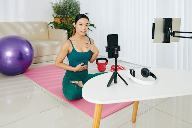 Młoda azjatycka blogerka fitness nagrywa wideo z treningu na swoim blogu