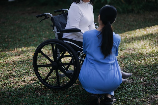 Młoda azjatycka fizjoterapeuta pracująca ze starszą kobietą podczas chodzenia z chodzikiem