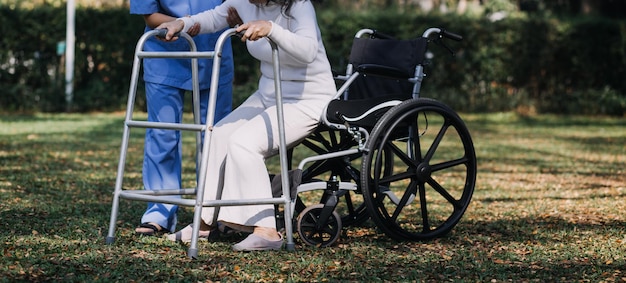 Młoda azjatycka fizjoterapeuta pracująca ze starszą kobietą podczas chodzenia z chodzikiem