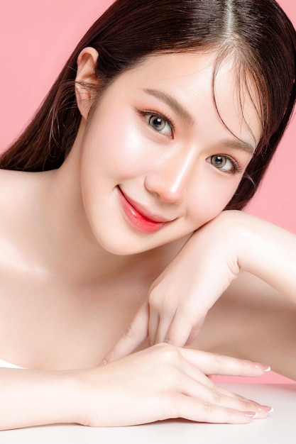 Młoda azjatycka kobieta długie włosy z naturalnym makijażem na twarzy ma pulchne usta i czystą świeżą skórę na odizolowanym różowym tle Portret uroczej modelki w studio Zabieg na twarz Kosmetologia