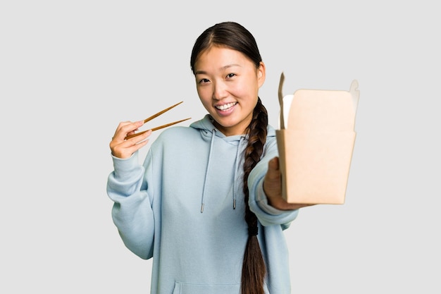Młoda azjatycka kobieta je ramen na wynos na białym tle