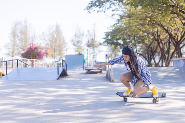 Młoda azjatycka kobieta jedzie oldschoolową deskorolkę w skateparku