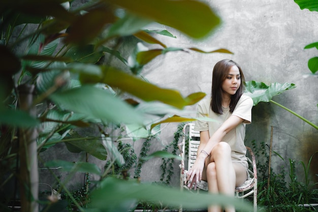 Młoda Azjatycka kobieta jest szczęśliwa i cieszy się w ogrodzie naturalnym miejscem do relaksu w wakacyjnej eko kawiarni na świeżym powietrzu
