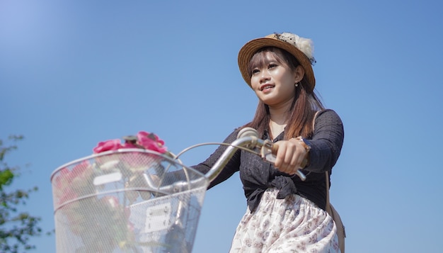 Młoda azjatycka kobieta jeżdżąca na rowerze w parku latem