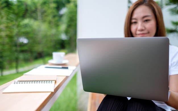 Młoda azjatycka kobieta korzystająca z laptopa i pracująca na nim na świeżym powietrzu