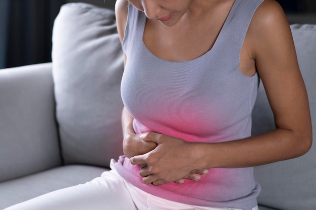 Młoda Azjatycka kobieta ma ból brzucha Miesiączkowy skurcze ból brzucha zatrucie pokarmowe Opieka zdrowotna i koncepcja medyczna