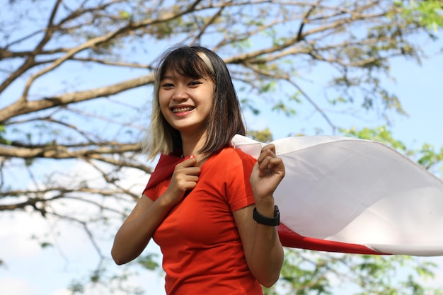 Zdjęcie młoda azjatycka kobieta niosąca indonezyjską flagę