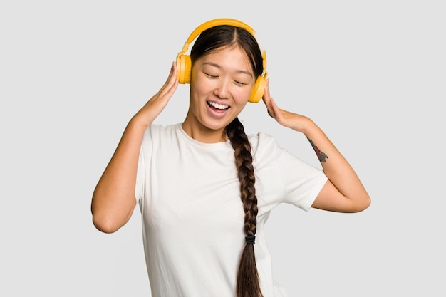 Młoda azjatycka kobieta słucha muzyki ze słuchawkami na białym tle