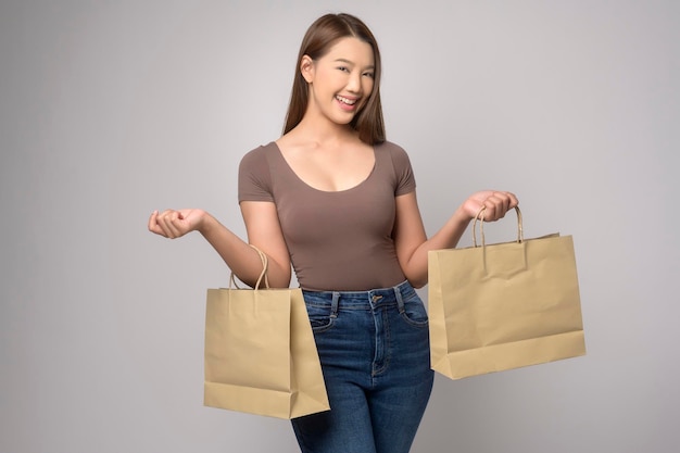 Młoda azjatycka kobieta trzyma torbę na zakupy na białym tle koncepcja zakupów i finansów w studio