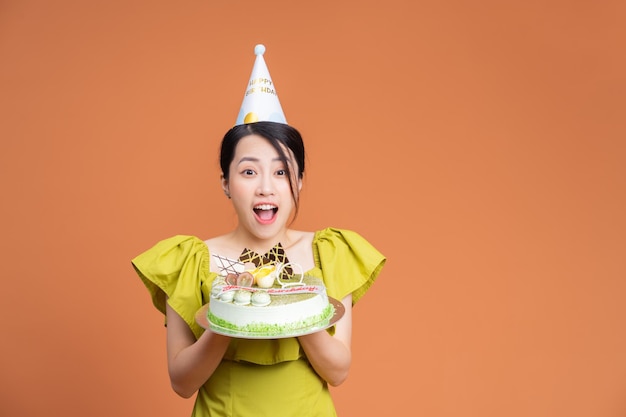 Młoda Azjatycka kobieta trzyma tort urodzinowy