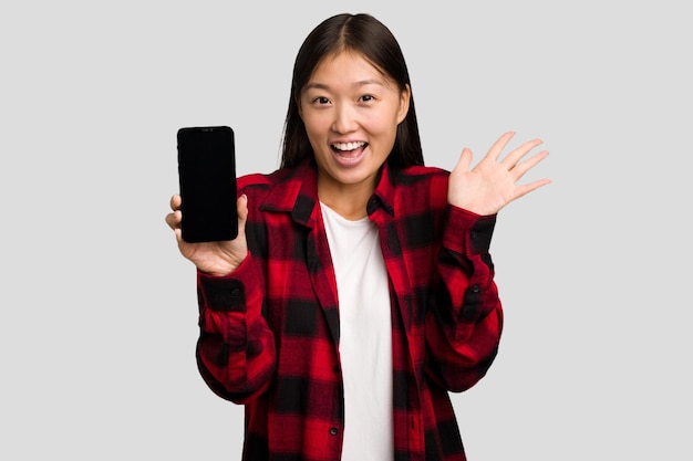 Młoda azjatycka kobieta trzymająca telefon komórkowy na białym tle