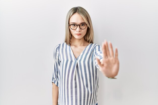 Młoda azjatycka kobieta ubrana w przypadkowe ubrania i okulary robi przestań śpiewać dłonią. wyraz ostrzegawczy z negatywnym i poważnym gestem na twarzy.