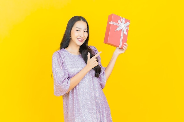 młoda azjatycka kobieta uśmiechająca się z czerwonym pudełkiem na żółto