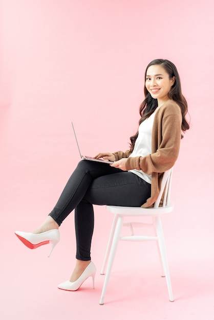 Młoda Azjatycka kobieta uśmiechnięta nastolatka siedząca na krześle przy użyciu laptopa do pracy z domu na covid-19 Crysis koronawirusa,