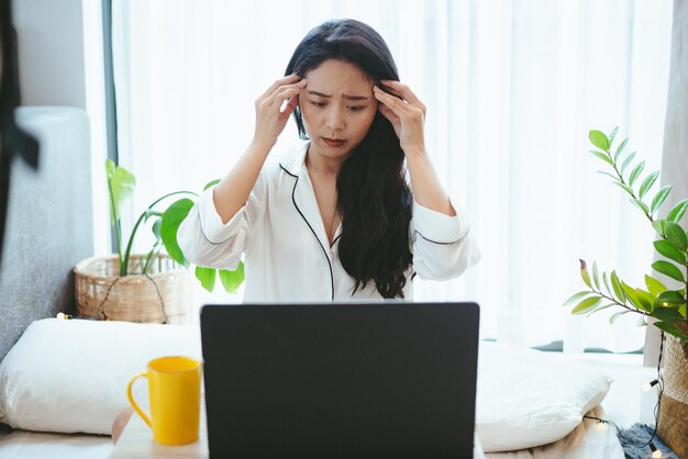 Młoda Azjatycka kobieta używająca laptopa do pracy online, niezależna kobieta pracująca w domu, wykorzystująca technologię komunikacji internetowej w cyberprzestrzeni do pracy jako bizneswoman