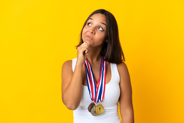 Młoda azjatycka kobieta z medalami na białym tle na białej ścianie i patrząc w górę