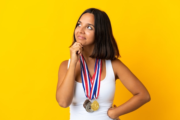 Młoda azjatycka kobieta z medalami na białym tle na białym tle, mając wątpliwości