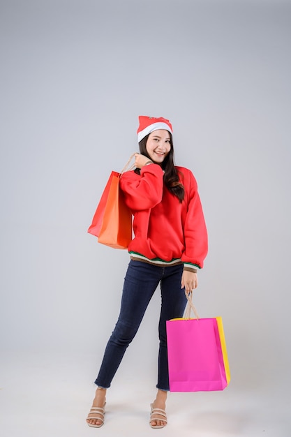 Zdjęcie młoda azjatycka kobieta z torby na zakupy i kapelusz santa