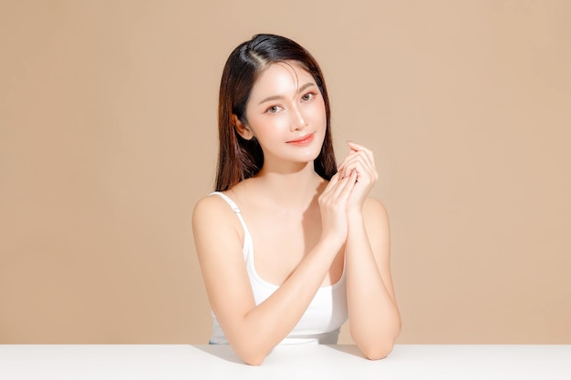 Młoda azjatycka modelka piękności z długimi włosami w koreańskim stylu makijażu na twarzy i doskonałą skórą na izolowanym beżowym tle Leczenie twarzy Kosmetologia Spa Estetyczna chirurgia plastyczna