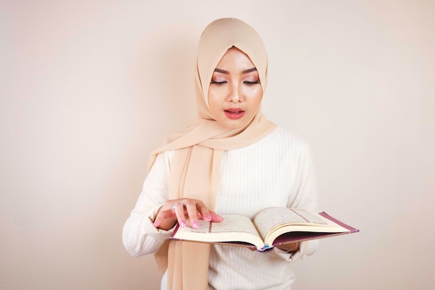 Młoda Azjatycka Muzułmanka nosząca chustę na głowie czytająca Koran